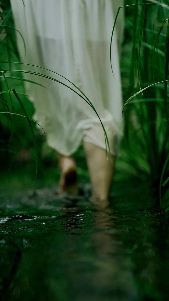 Agnieszka in white walking through a green waterscape